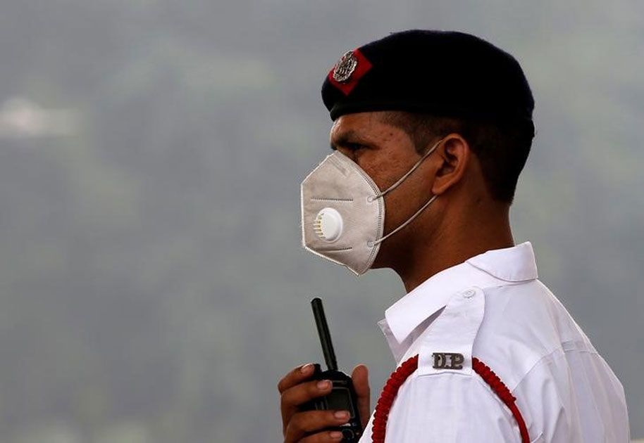 A traffic policeman wearing a mask controls the traffic at a busy road on a smoggy morning in New Delhi. A traffic policeman wearing a mask controls the traffic at a busy road on a smoggy morning in New Delhi.